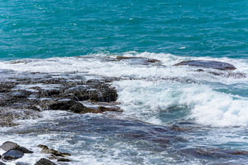 the waves of the turquoise sea break into foam on the shore stones