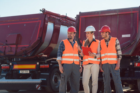 Truck drivers and dispatcher talking in front of lorries in freight forwarding company