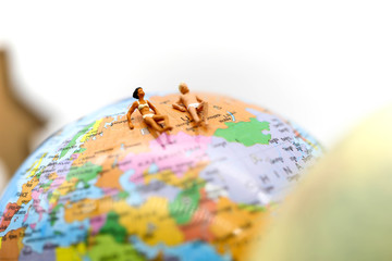 Miniature people wearing swimsuit relaxing on book and world map background,holiday, vacation concept.