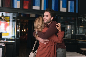 Hold me. Pleased young couple embracing and man smiling