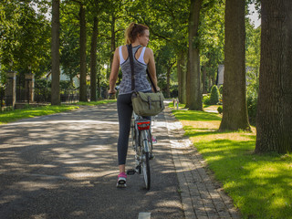 A sports girl on a bicycle with a school bag on a country road. Back to school concept.