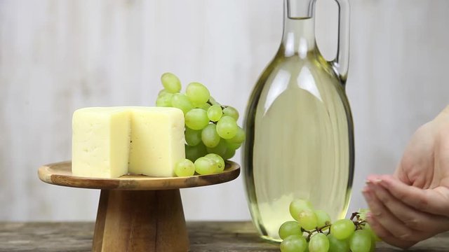 Woman's hand with a glass of wine on a background of grapes and cheese. Woman nils and drinks wine.