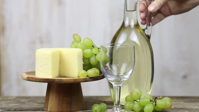 Woman's hand with a glass of wine on a background of grapes and cheese. Woman nils and drinks wine.