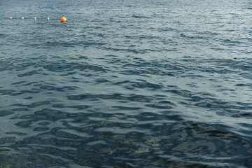 Gloomy sea shore in the evening without people. In the water near the shore floats buoy protecting the safe area for swimming
