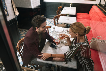 Sincere conversation. Top view of optimistic jolly couple holding hands and drinking wine