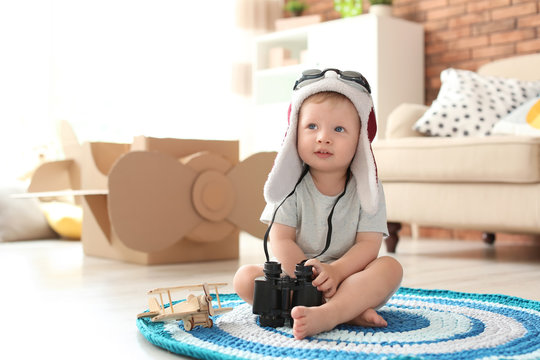 Adorable little child playing with binoculars at home