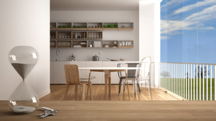 Wooden table, desk or shelf with crystal modern hourglass measuring the passing time in a countdown over blurred minimalistic kitchen, architecture interior design, copy space background