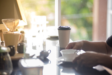 barista man holding cup of hot coffee to drink in cafeteria with copy space for text on advertisement board