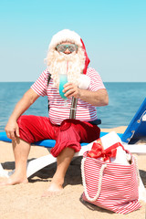 Obraz premium Authentic Santa Claus with cocktail resting on lounge chair at resort