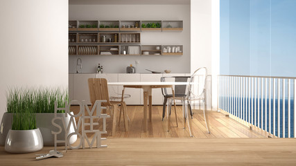 Wooden table, desk or shelf with potted grass plant, house keys and 3D letters home sweet home, over modern kitchen, architecture interior design, copy space background