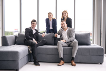 Portrait business people in office sitting on sofa smiling