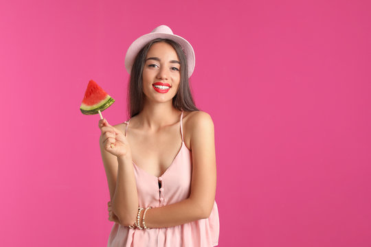 Beautiful young woman posing with watermelon on color background