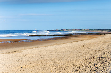 Deserted Sandy Beach on the Coast of England under Blue Sky. A Lighthouse is Visible in Background. Blyth, Nortumberland, England.
