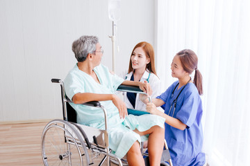 Fototapeta premium Beautiful Asian doctor and nurse taking care of senior patient in wheelchair