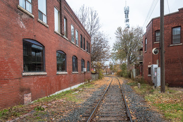 Fototapeta na wymiar Railway Track between Two Brick Warehouses on a Cloudy Autumn Day