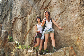 Young friends near steep cliff on summer day. Camping season
