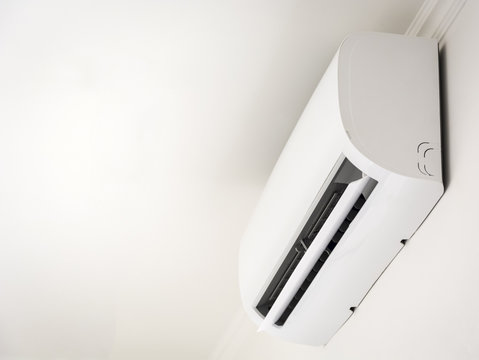 Close up white air conditioner swing mounted on a white wall
