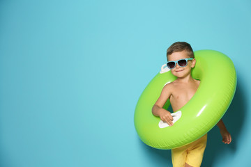 Fototapeta premium Cute little boy with inflatable ring on color background