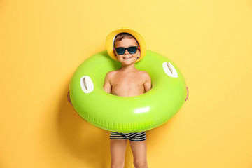 Fototapeta premium Cute little boy with inflatable ring on color background