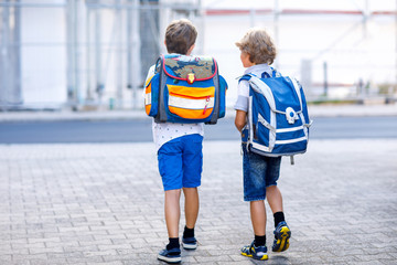 Two little kid boys with backpack or satchel. Schoolkids on the way to school. Healthy adorable...