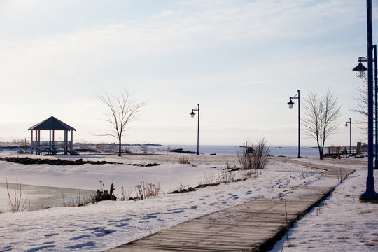 Wood path walkway to pavilion at frozen lake shore on a calm winter morning