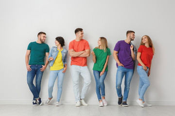 Group of young people in jeans and colorful t-shirts near light wall