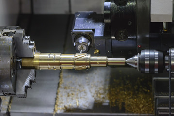 The CNC turning or lathe machine cutting groove slot at the brass shaft  by the milling spindle. Hi - technology manufacturing process.