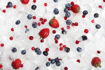 Frozen berries and ice cubes as background