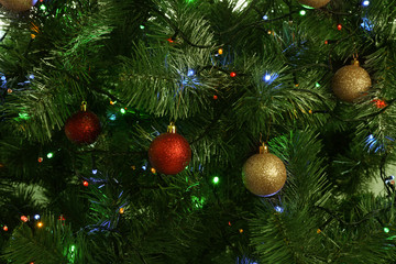 Fir tree with festive decor and glowing Christmas lights as background