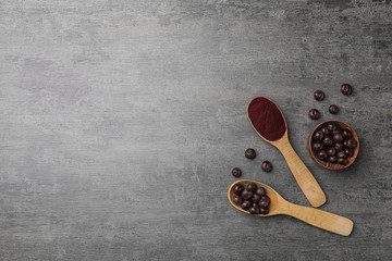 Flat lay composition with acai powder and fresh berries on gray table