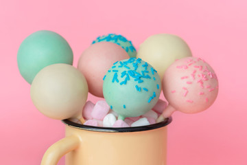 icing pop cakes and marshmallows over pink background, close up