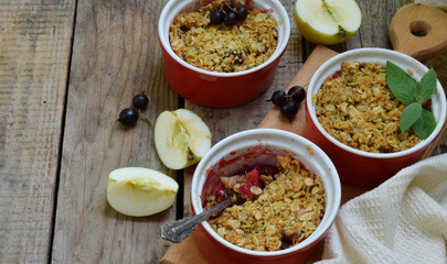 Fruits casserole or crumble with apples and black currant in red cup ramekin. Copy space. Berry and fruits dessert ready to eat. Homemade baking. Healthy pastries. Rustic photo