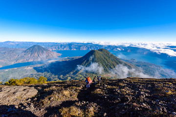 Hiker with panorama view of Lake Atitlan and volcano San Pedro and Toliman early in the morning from peak of volcano Atitlan, Guatemala. Hiking and climbing on Vulcano Atitlan.