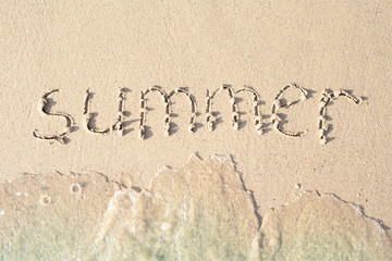 Word Summer written in the sea sand. Waves washed away the inscription.