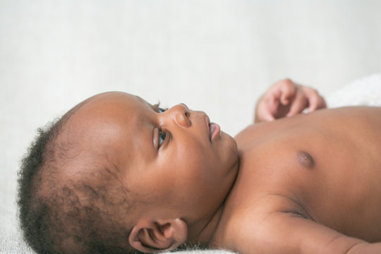 Profile of Awake Newborn Baby hands on Cream White Background