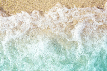 Soft waves with foam on sandy beach. Top view.