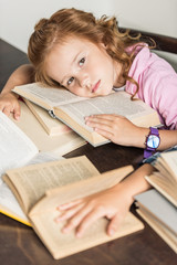 high angle view of exhausted little schoolgirl lying on books