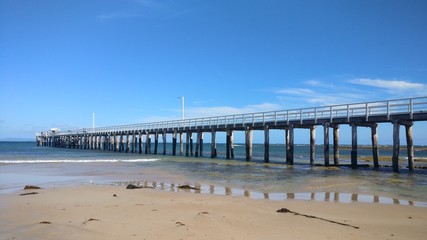 Fototapeta na wymiar Long pier on shallow beach