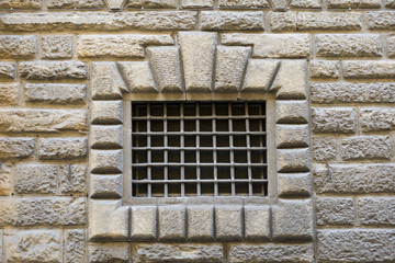  Decorative window with bars in a stone wall. Florence, Italy