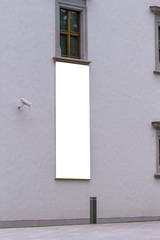 Mock up. Blank white vertical banner on building facade. Empty advertising flag mock up on the wall