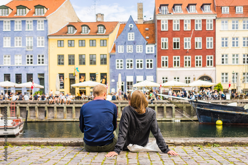 Wall mural Tourists enjoying the scenic summer view of Nyhavn pier. Colorful building facades with boats and yachts in the Old Town of Copenhagen, Denmark