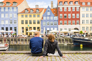 Tourists enjoying the scenic summer view of Nyhavn pier. Colorful building facades with boats and...