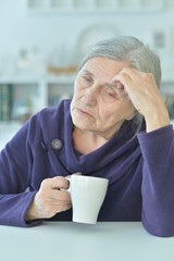 Portrait of a sad old woman drinking tea