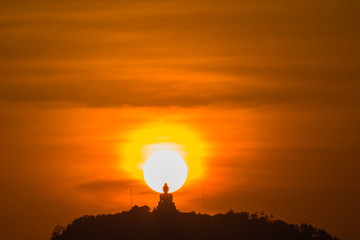 stunning red sky sunset the round sun is on the back of Phuket big Buddha on the high mountain .landmark of Phuket island can see isolated Phuket big Buddha from distance
