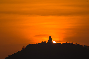 stunning red sky sunset the round sun is on the back of Phuket big Buddha on the high mountain .landmark of Phuket island can see isolated Phuket big Buddha from distance