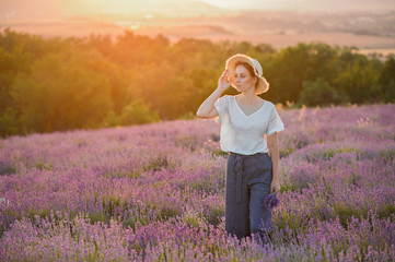 Beautiful woman in a field of lavender on sunset. Woman in amazing dress walk on the lavender field.