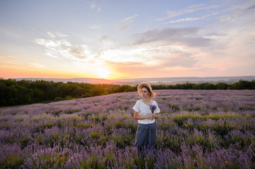 Fototapeta na wymiar Beautiful woman in a field of lavender on sunset. Woman in amazing dress walk on the lavender field.