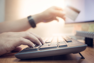 Close-up Man's hands holding a credit card and using computer keyboard for online shopping