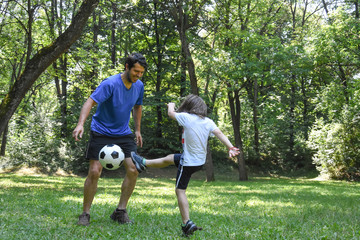 Father and son play with ball in autumn park. Happy family play soccer in public park