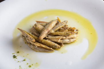 Fried fish with oil on a white plate